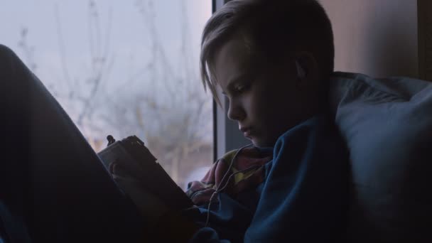 Ребенок с помощью планшета на подоконнике — стоковое видео
