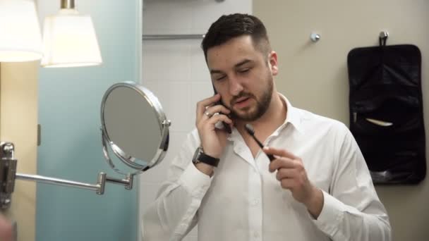 Зайнятий бізнесмен розмовляє по телефону під час чищення зубів — стокове відео