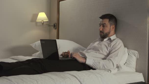 Бизнесмен работает с ноутбуком на кровати — стоковое видео