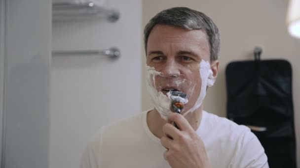 Взрослый мужчина бреется в ванной — стоковое видео