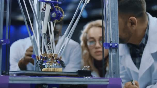 Onderzoekers kijken naar 3D-drukmachine in proces — Stockvideo