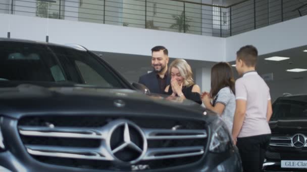 Счастливая семья получает новый автомобиль в салоне — стоковое видео