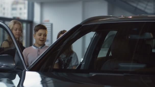 Familia tomando asientos en coche nuevo en el salón — Vídeo de stock