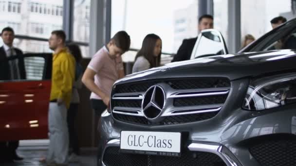 Lesklý moderní auto v showroomu s návštěvníky — Stock video