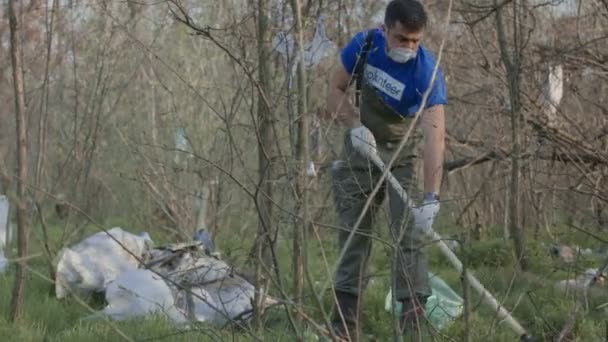 Чоловік в респіраторі прибирає в лісі — стокове відео