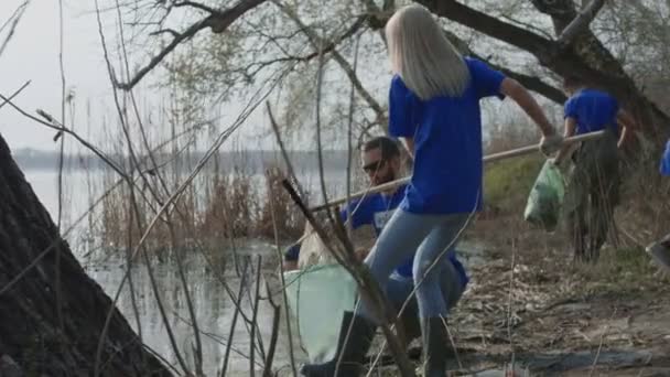 Personer rengöring dammen shore i skogen — Stockvideo