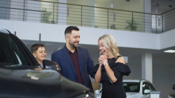 Família feliz recebendo carro novo no salão — Fotografia de Stock