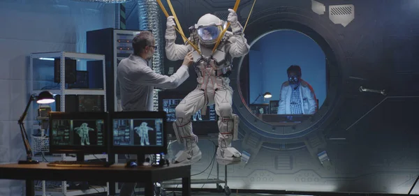 宇宙飛行士はバンドにぶら下がりながら手足を動かす — ストック写真