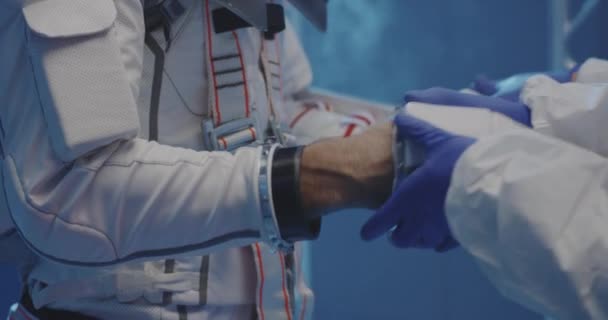 Scientist helping astronaut to put on gloves — Stock Video