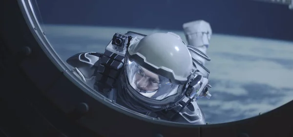 นักบินอวกาศลอยผ่านหน้าต่างยานอวกาศ — ภาพถ่ายสต็อก