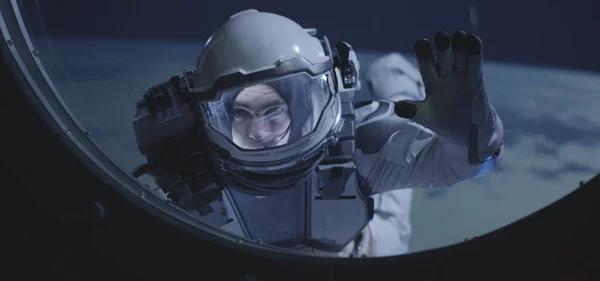 Astronaut drijvend door ruimteschepen raam — Stockfoto