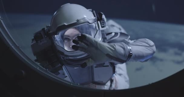 Космонавт, плывущий по окну космического корабля — стоковое видео
