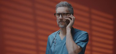 Erkek doktor telefon görüşmesi yapıyor.