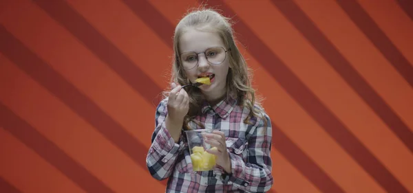 Flicka äta ananas från plastmugg — Stockfoto