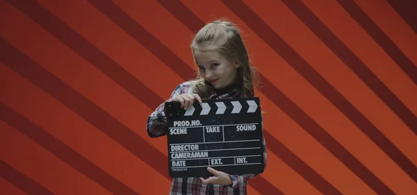 Girl clapping clapboard and raising eyebrows — Stock Photo, Image