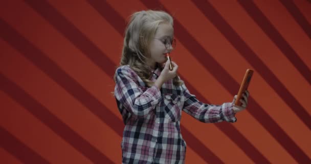 Mädchen trägt Lippenstift auf, während sie aufs Smartphone schaut — Stockvideo