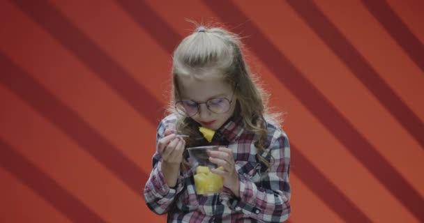 Девушка ест ананас из пластиковой чашки — стоковое видео