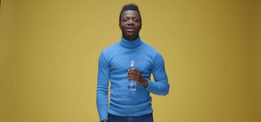 Adam şişeyi açıyor ve içiyor.