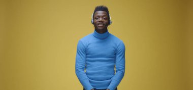 Kulaklık takmış bir adam kamerayla konuşuyor.