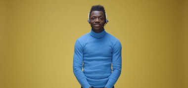 Kulaklık takmış bir adam kamerayla konuşuyor.