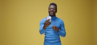 Genç adam telefonda görüntülü konuşma yapıyor.