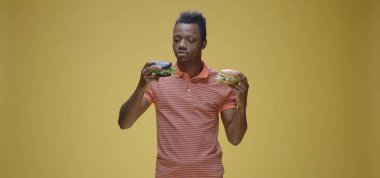 Genç adam iki sandviç yiyor.