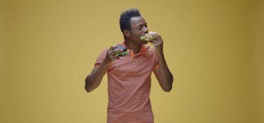 Genç adam iki sandviç yiyor.