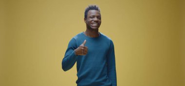 Genç adam kameraya başparmak kaldırıyor.