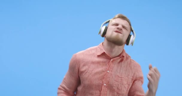 Young man air wearing headphones and playing air guitar — Stock Video