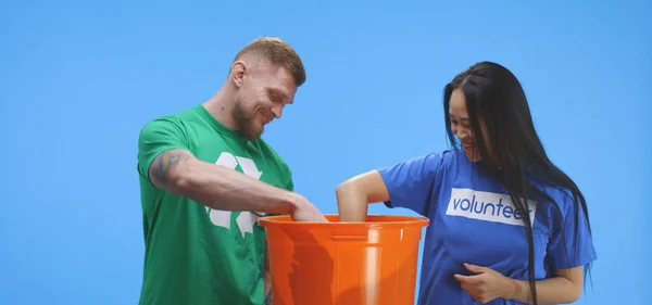 Homme et femme éco-conscients mettant la bouteille dans le seau — Photo