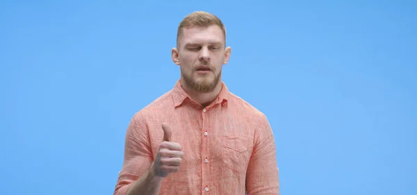 Junger Mann gibt augenzwinkernd die Daumen hoch — Stockfoto