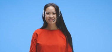 Kulaklık takmış genç bir kadın konuşuyor.