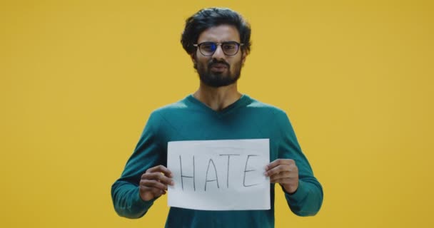 Молодий чоловік тримає знак ненависті і говорить — стокове відео
