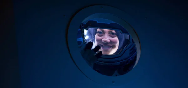 女宇航员从宇宙飞船上对着相机挥手 — 图库照片