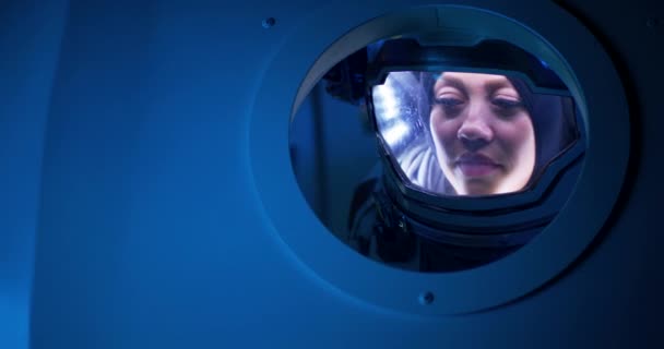 Astronauta femenina mirando desde el ojo de buey de la nave espacial — Vídeos de Stock