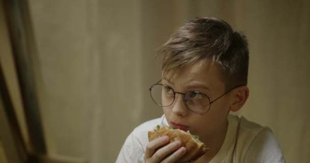 Хлопчик дивиться на картину під час їжі — стокове відео