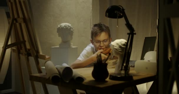 Молодой художник ест в студии — стоковое видео
