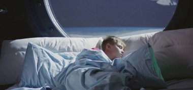Çocuk uzay gemisinde uyuyor.