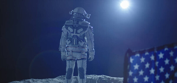 Астронавт, стоящий за флагом США

