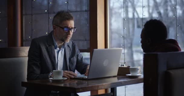 Бизнесмен разговаривает с клиентом в кафе — стоковое видео