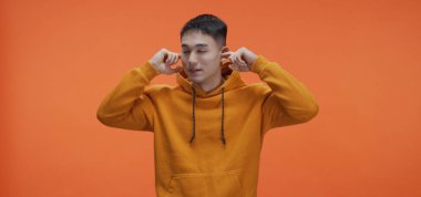 Genç adam kulaklarını tıkıyor.