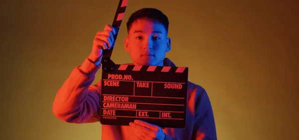 Young man using clapperboard — Stockfoto