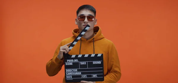 Young man using clapperboard — Stockfoto