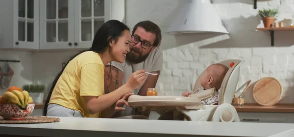 Mãe alimentando seu bebê na cozinha — Fotografia de Stock