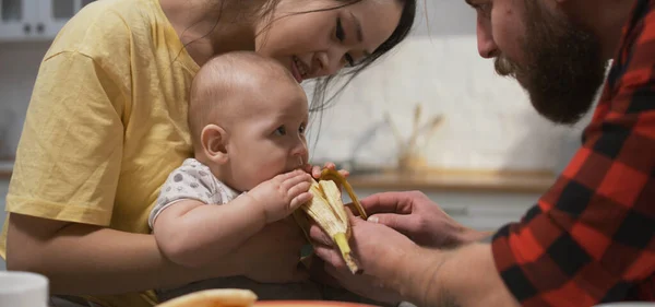 Young couple feeding baby with banana — Stock Photo, Image