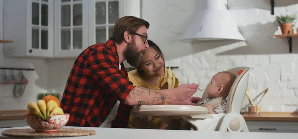Junges Paar füttert sein Baby in Küche — Stockfoto