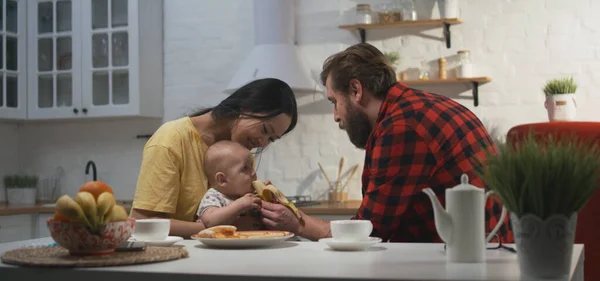 Jovem casal alimentando bebê com banana — Fotografia de Stock