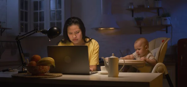 Madre joven con el bebé trabajando en el ordenador portátil — Foto de Stock