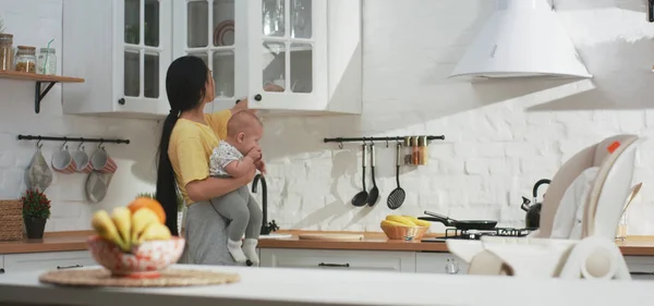 Young mother doing housework while holding baby — Stok fotoğraf