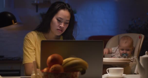 Madre joven con el bebé trabajando en el ordenador portátil — Vídeo de stock